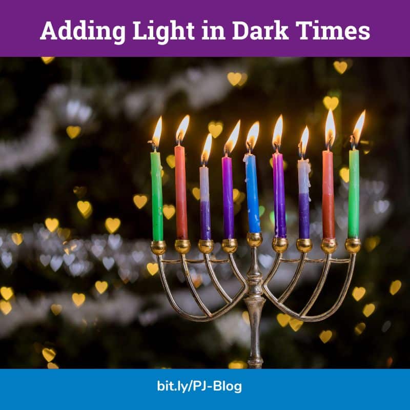 An image of a lit menorah with the words, "adding light in dark times"